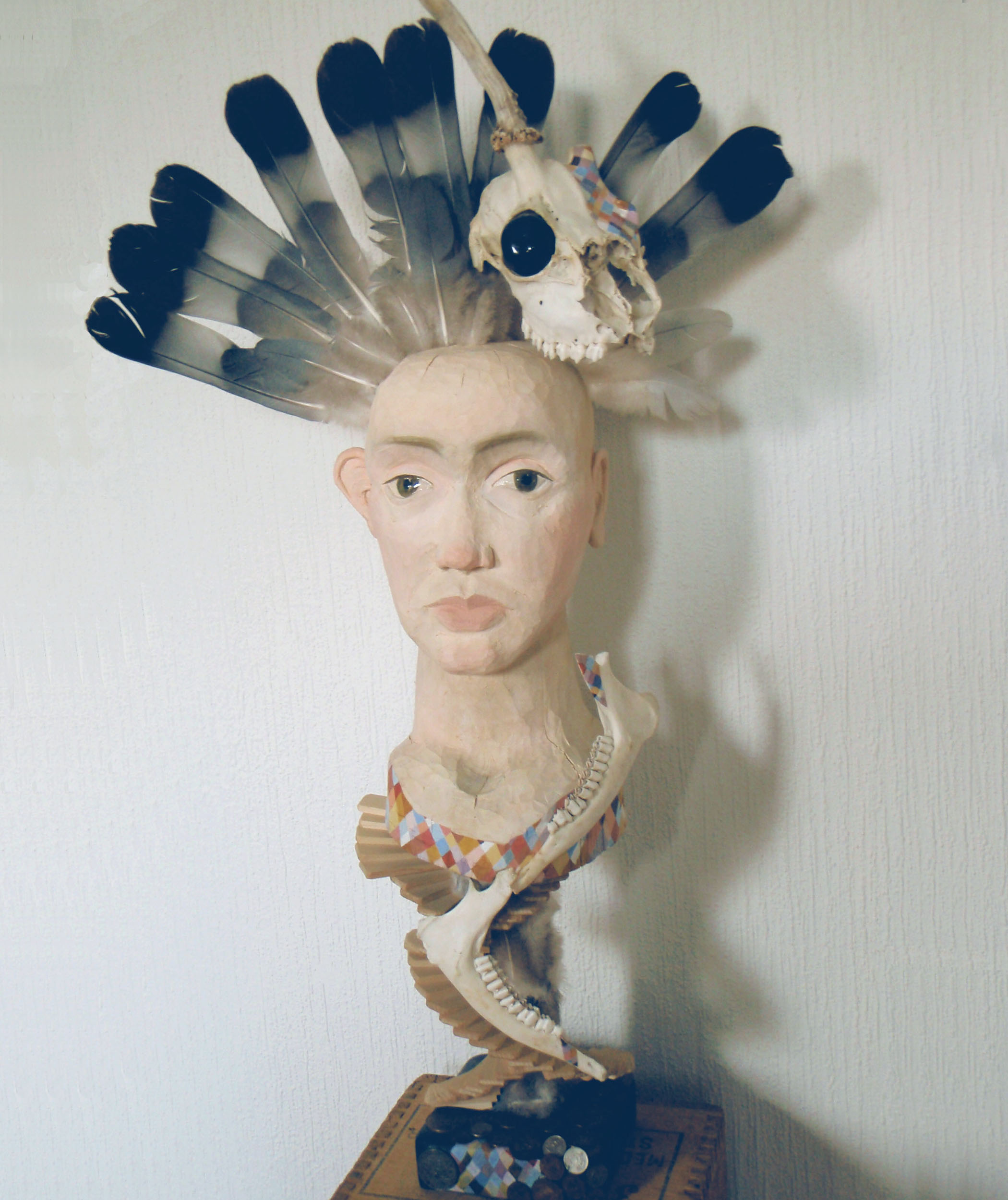 Skulptur av trä, rådjursskalle och duvfjädrar